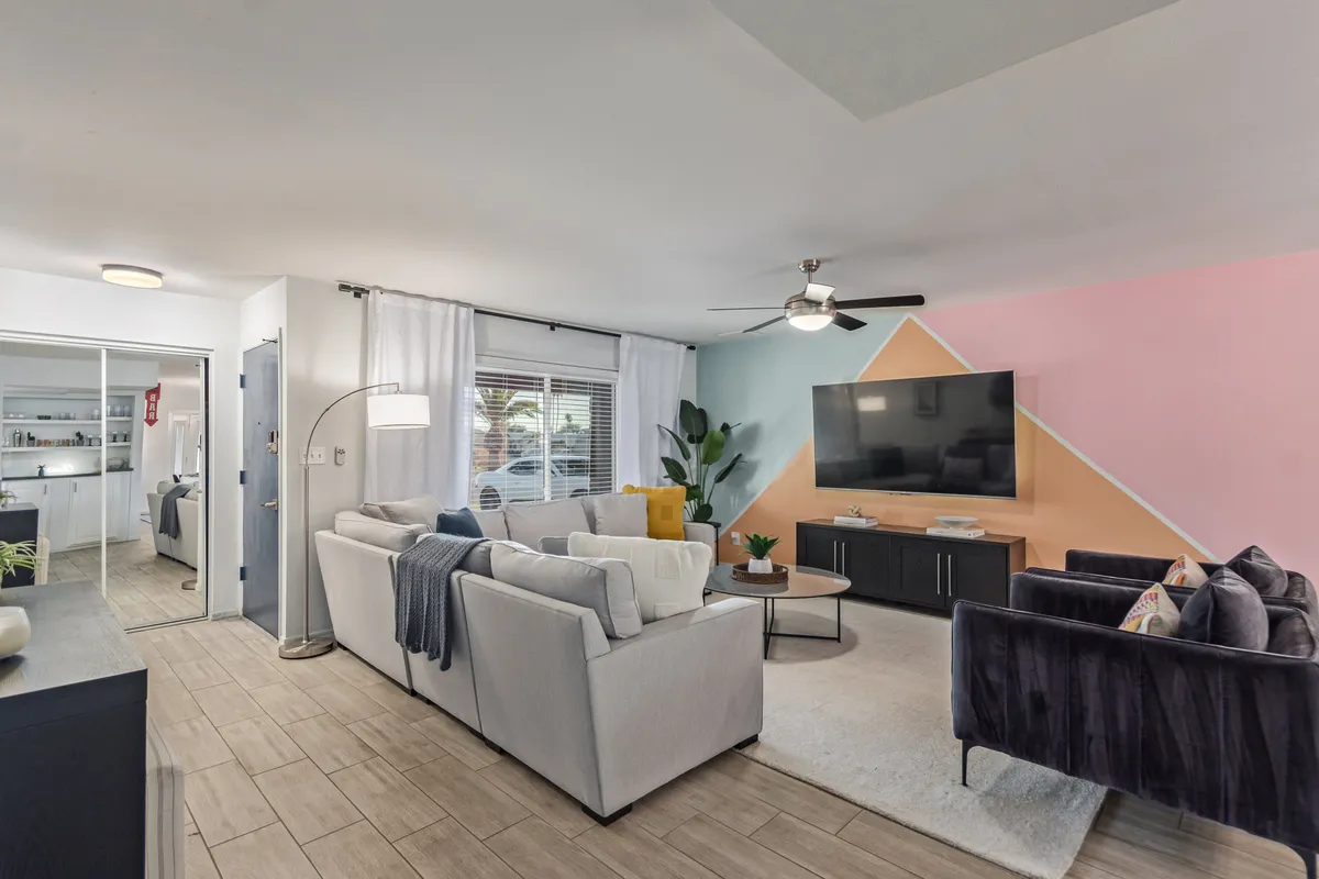 A modern living room scene with a comfortable sofa set, stylish decorative wall, TV, and contemporary lighting. The seating arrangement is ideal for both relaxation and informal work sessions, with a calm, inviting ambiance.