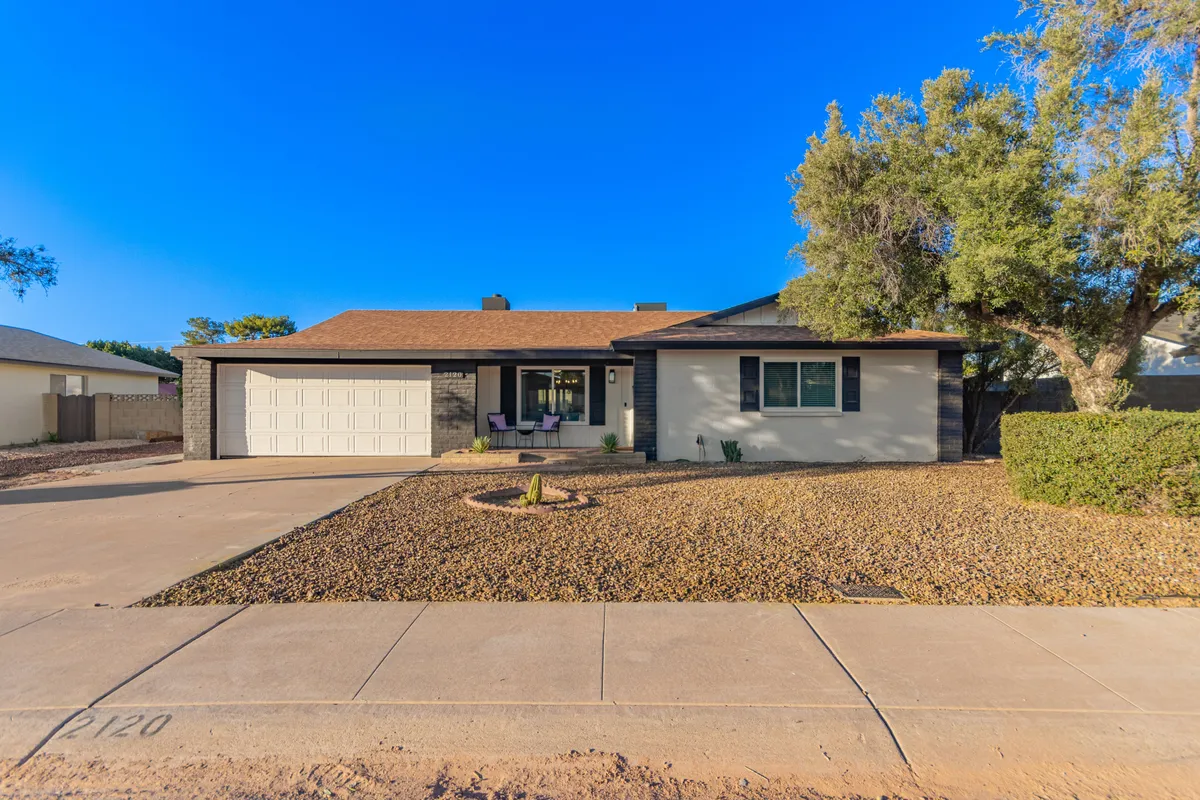 An inviting shot of the home's front porch with comfortable chairs, mature landscaping, and large windows. The image conveys a relaxed, welcoming atmosphere—perfect for quiet mornings with coffee or transitioning from work mode to exploration of the vibrant Tempe neighborhood.